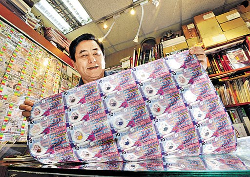 錢幣買賣商陳榮輝向記者展示港幣10元連張，他表示，「膠蟹」炒得起全靠內地需求。 ...